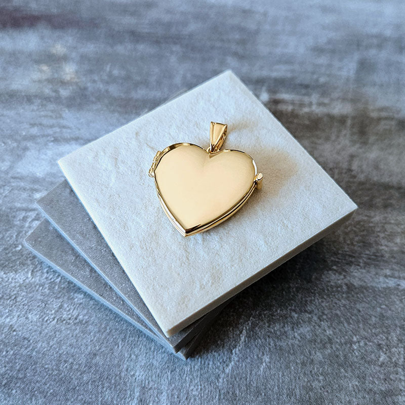 Gold heart-shaped locket on a gray textured surface