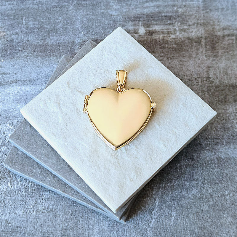 Gold heart-shaped locket on a gray textured surface