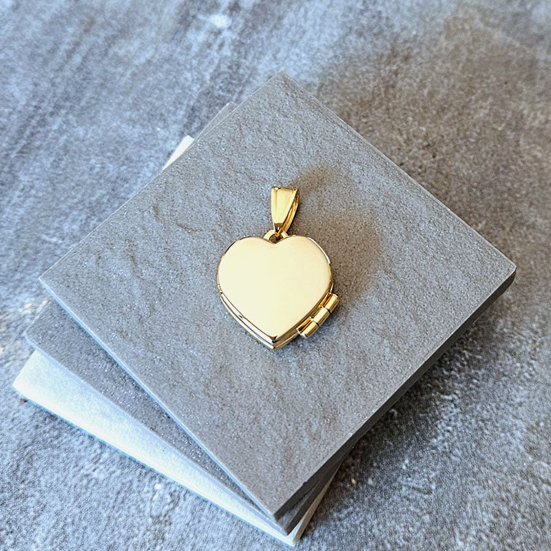 Gold heart-shaped locket on a gray stone surface