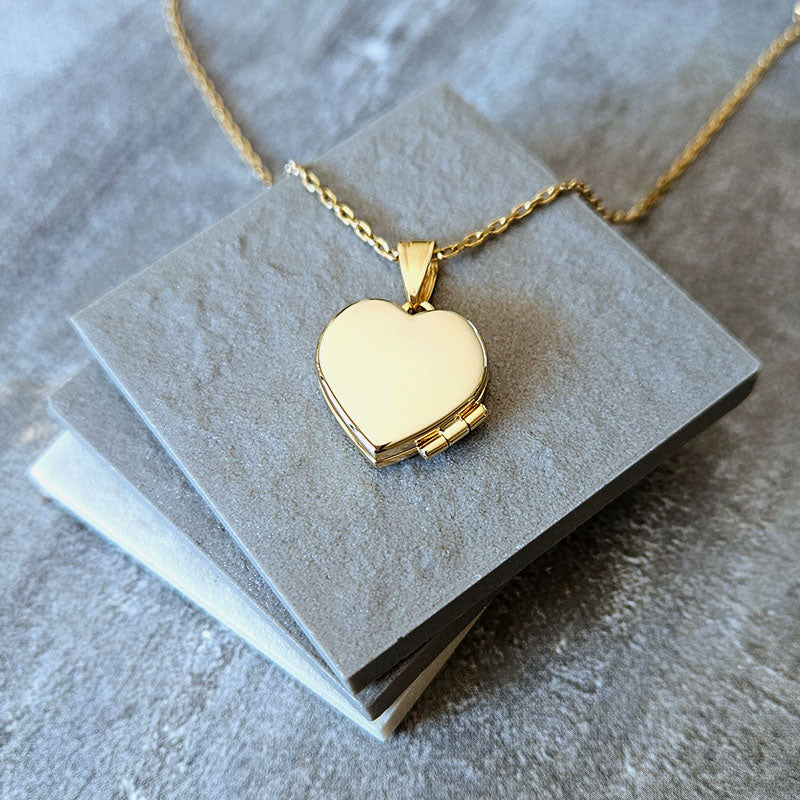 Gold heart-shaped locket on a gray card with a gray background