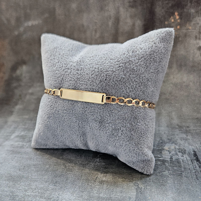 Gold bracelet on a gray textured pillow against a gray background