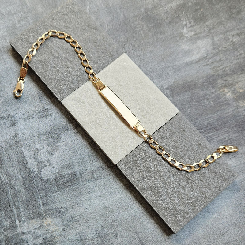 Gold bracelet with a bar clasp on a gray surface