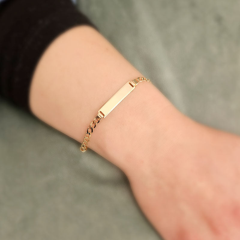 Gold bracelet on a wrist with a neutral background