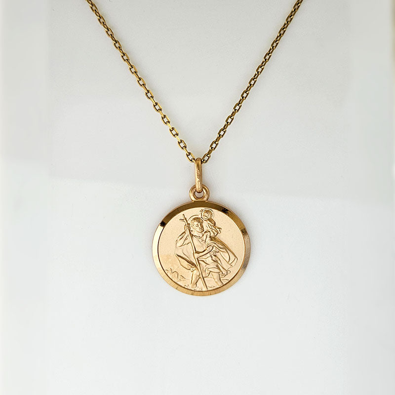 Gold necklace with a round pendant on a light gray background