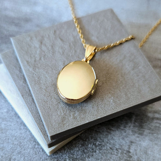 Gold locket necklace on a gray textured surface