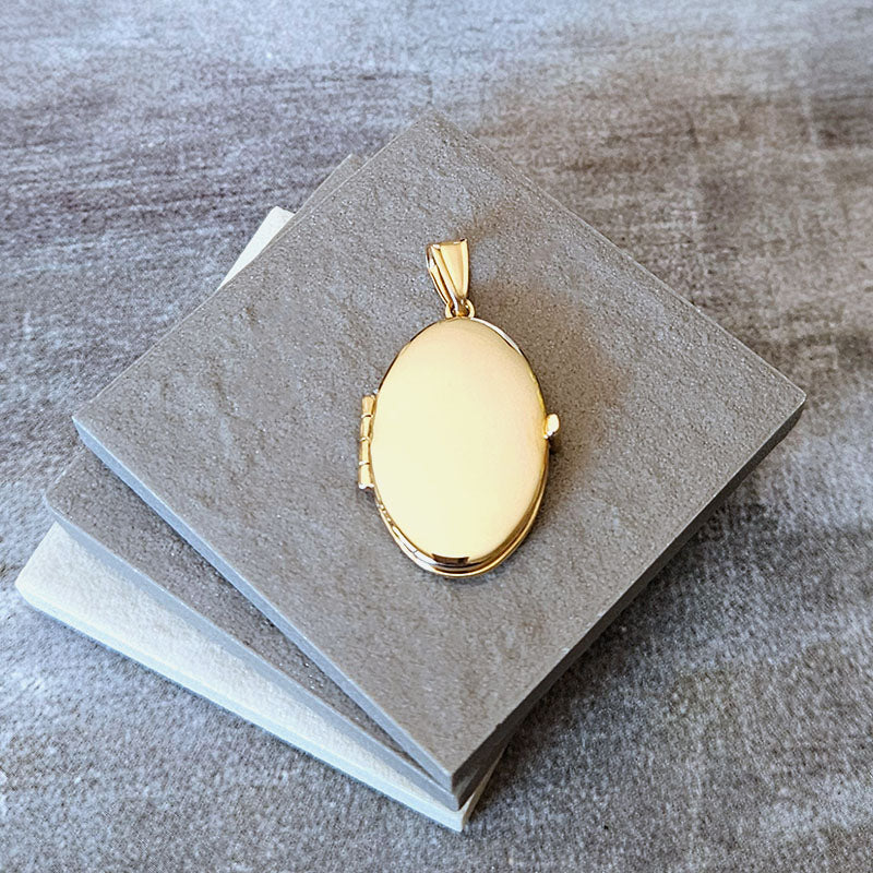Gold locket on a stack of gray papers with a textured background