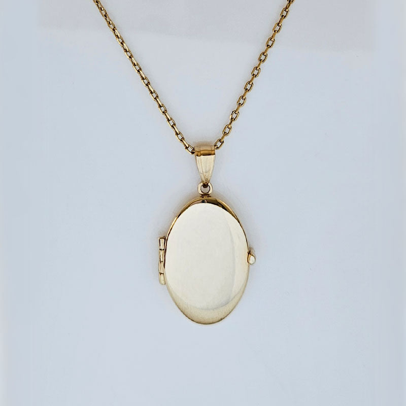 Gold locket necklace on a light gray background