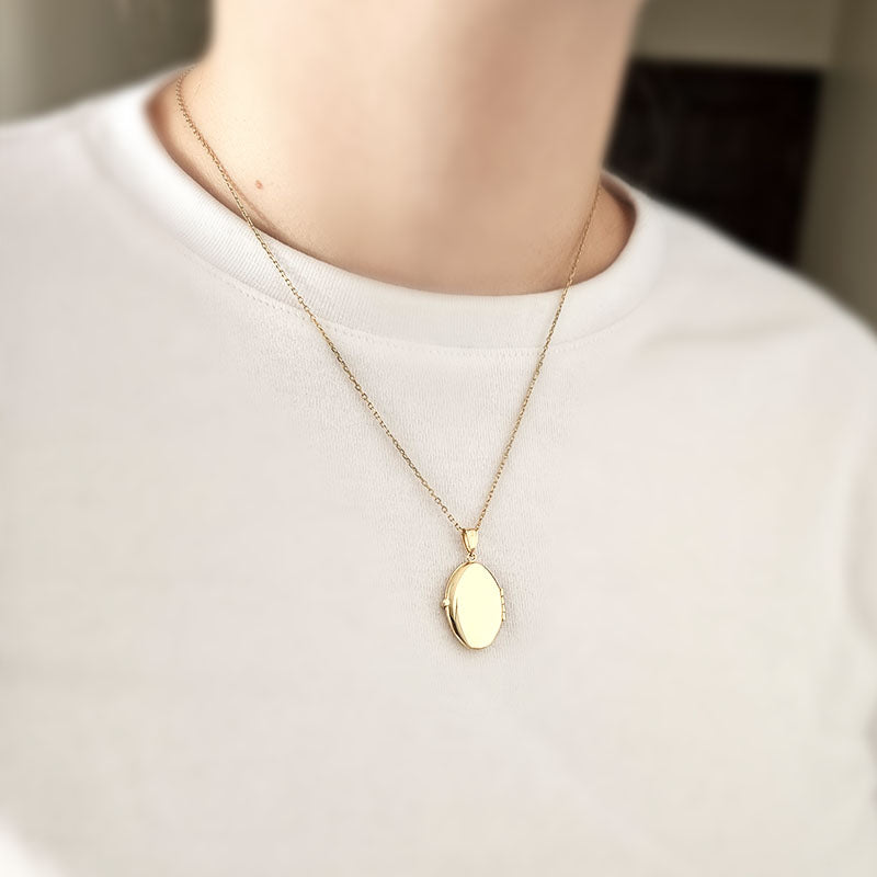 Gold necklace with a pendant on a mannequin wearing a white shirt.