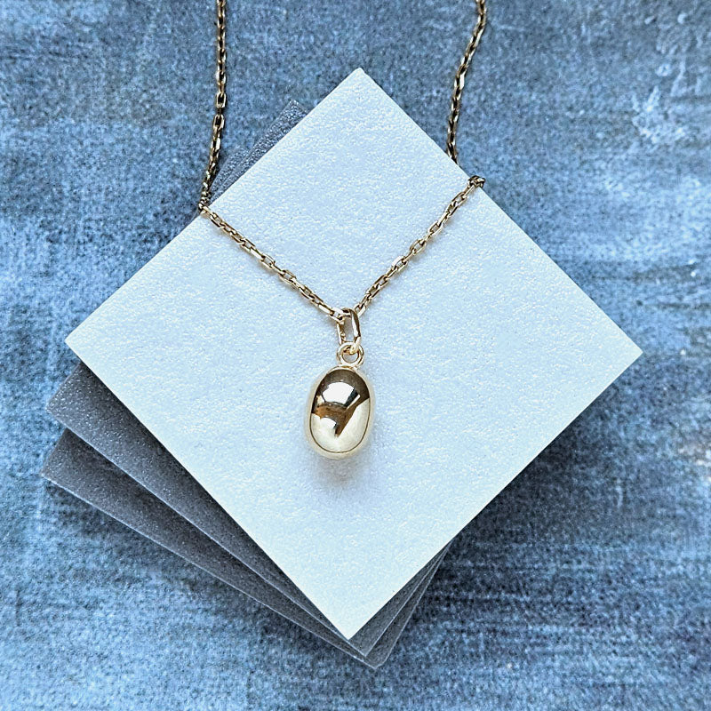 Gold necklace with a pendant on a blue textured background