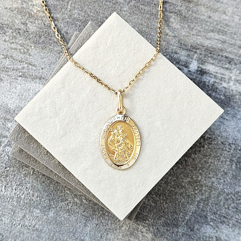 Gold St Christopher necklace with a pendant on a gray surface