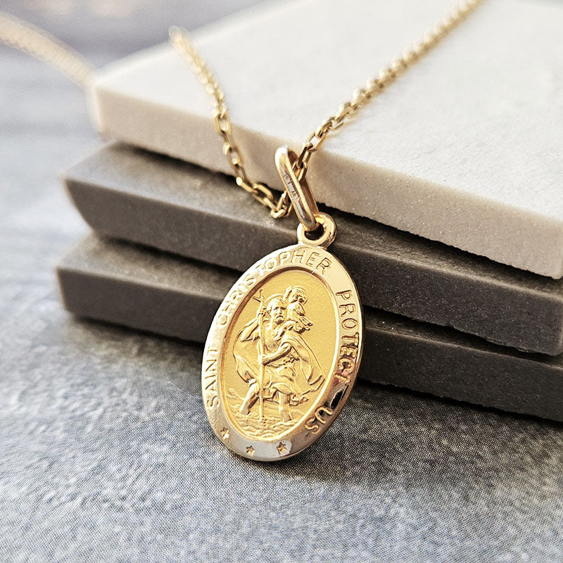 Gold Saint Christopher pendant necklace on a gray surface