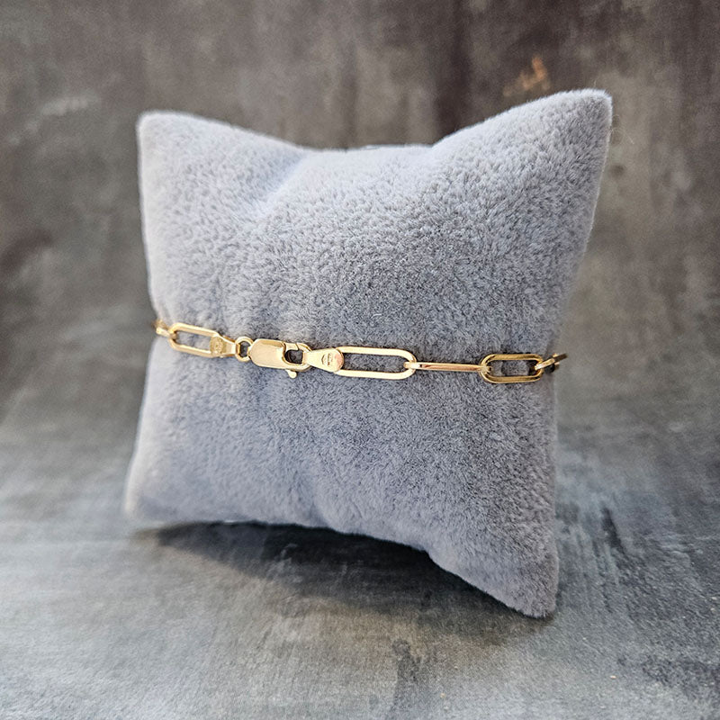Gold bracelet on a gray textured pillow