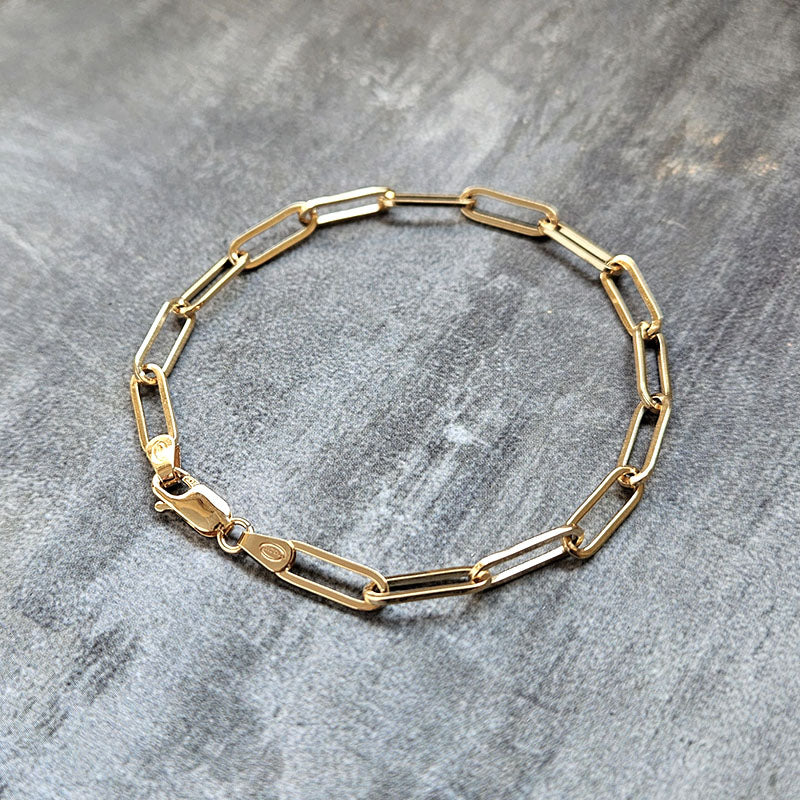 Gold chain bracelet on a gray textured surface