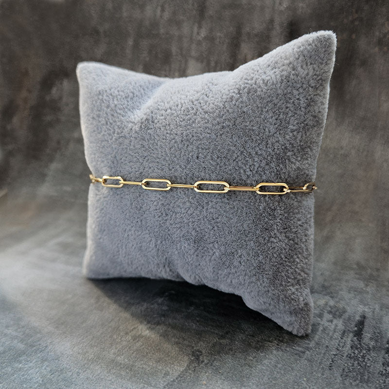 Gold bracelet on a gray textured pillow