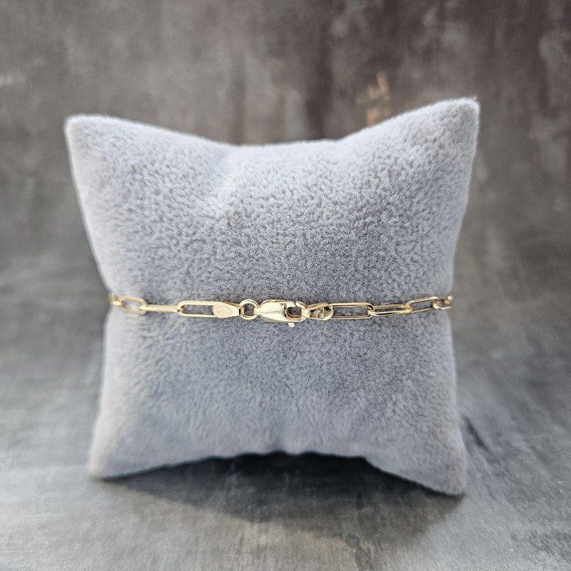 Gold bracelet on a gray textured pillow with a gray background