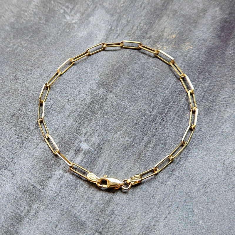 Gold chain bracelet on a gray surface