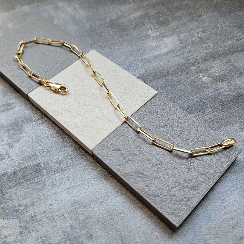 Gold chain necklace on a gray stone surface