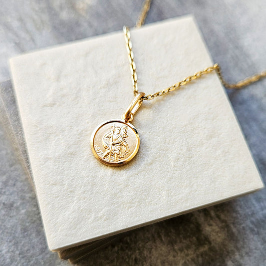 Gold necklace with a round pendant on a white box