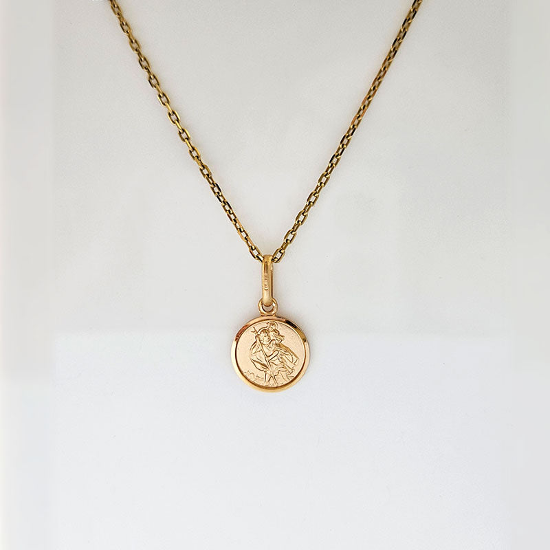 Gold necklace with a round pendant on a light gray background