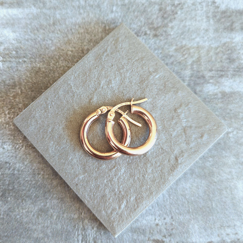 Pair of gold hoop earrings on a light stone surface