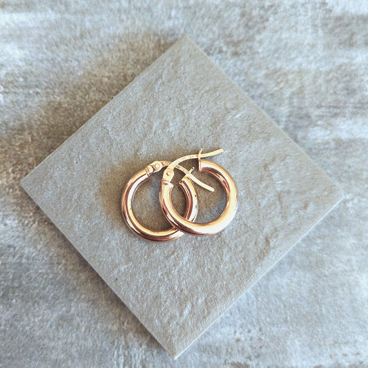 Pair of gold hoop earrings on a light stone surface