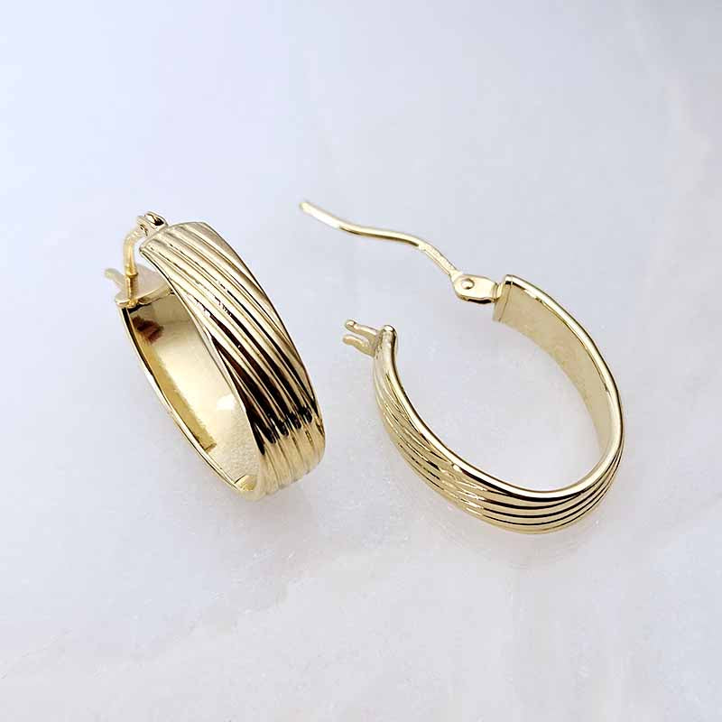 A pair of gold hoop earrings with a textured, ribbed design, displayed on a clean white background.