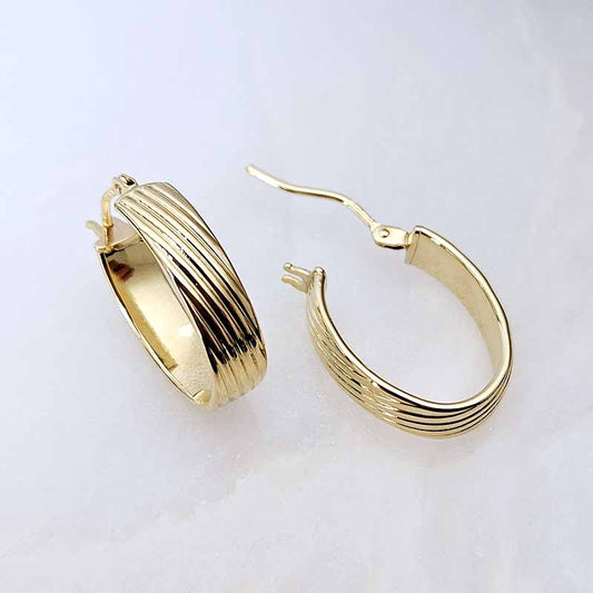 A pair of gold hoop earrings with a textured, ribbed design, displayed on a clean white background.