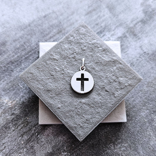 Silver cross pendant on a gray stone surface