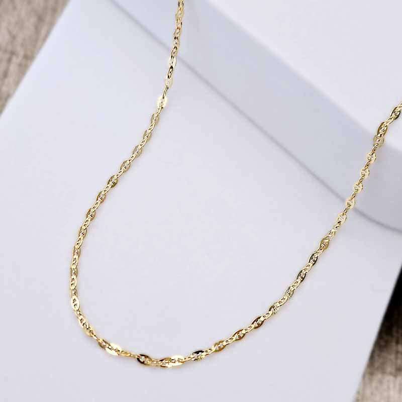 A gold twisted rope chain necklace draped over a white display box.