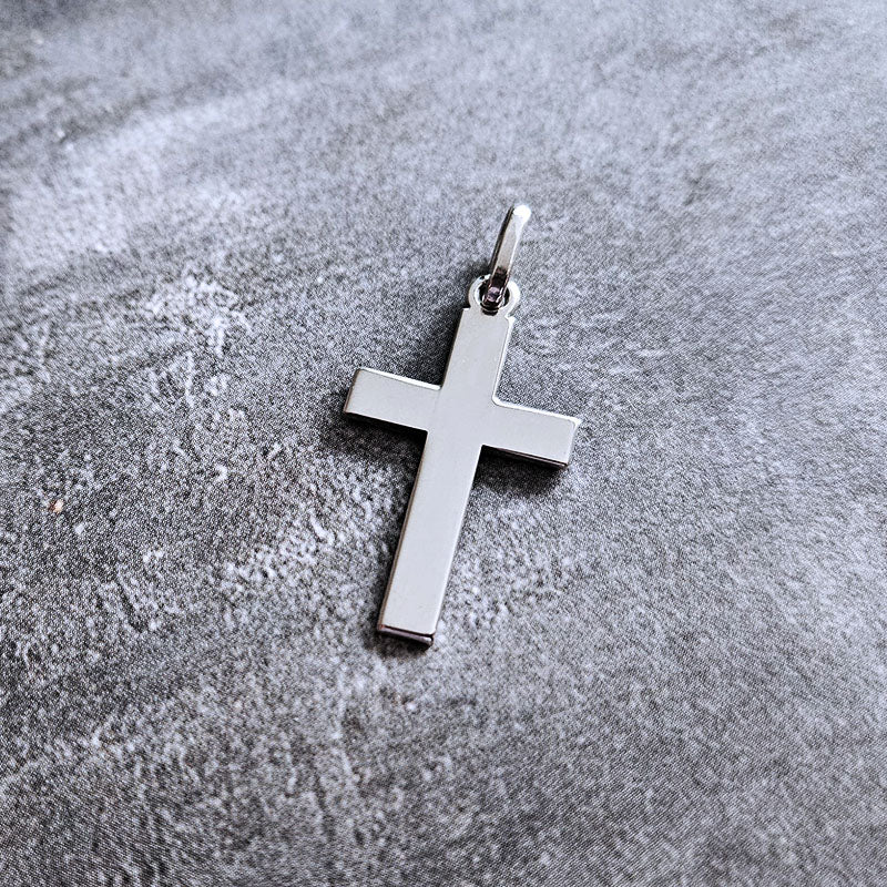 Silver cross pendant on a textured gray surface