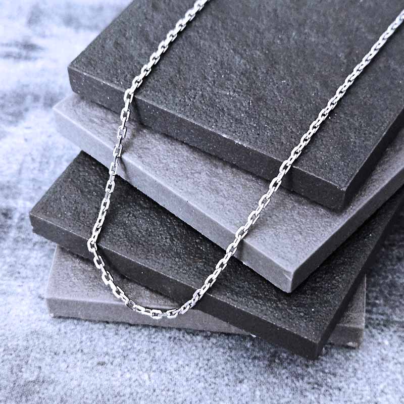 Platinum chain necklace on a stack of gray stone tiles