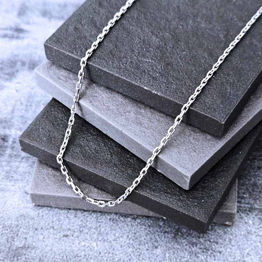 Platinum chain necklace on a stack of gray stone tiles