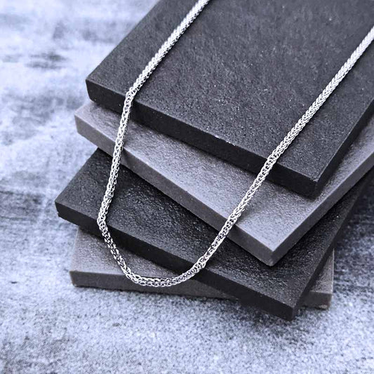 Platinum chain necklace on a stack of black stone slabs