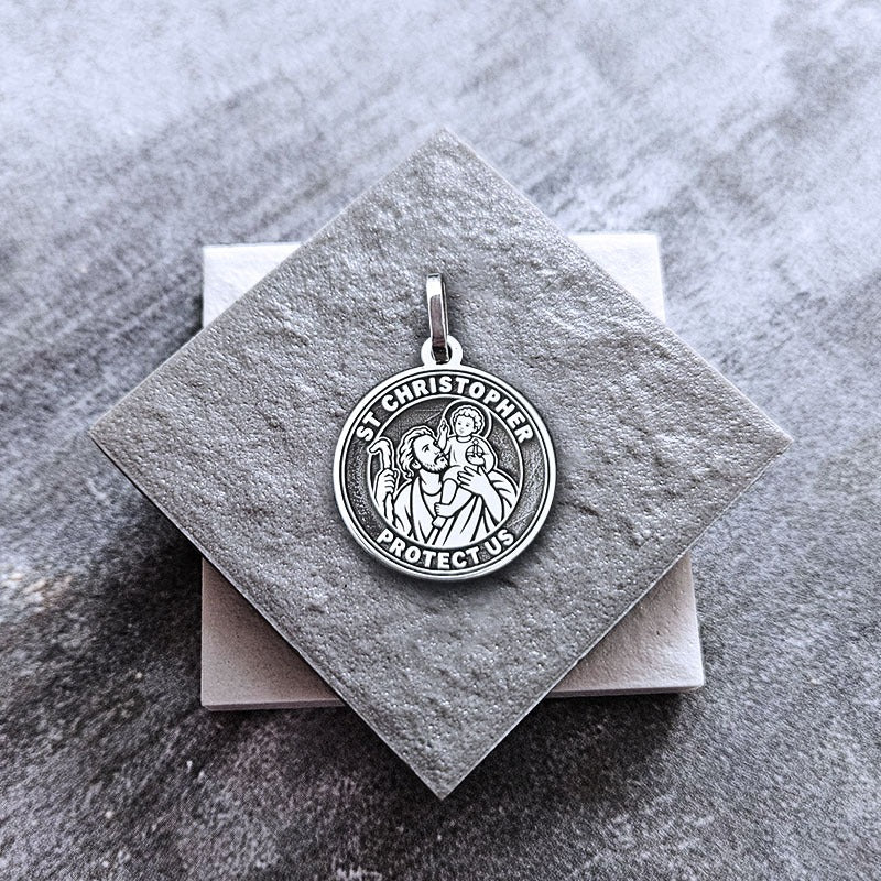 Silver St. Christopher pendant on a gray stone surface
