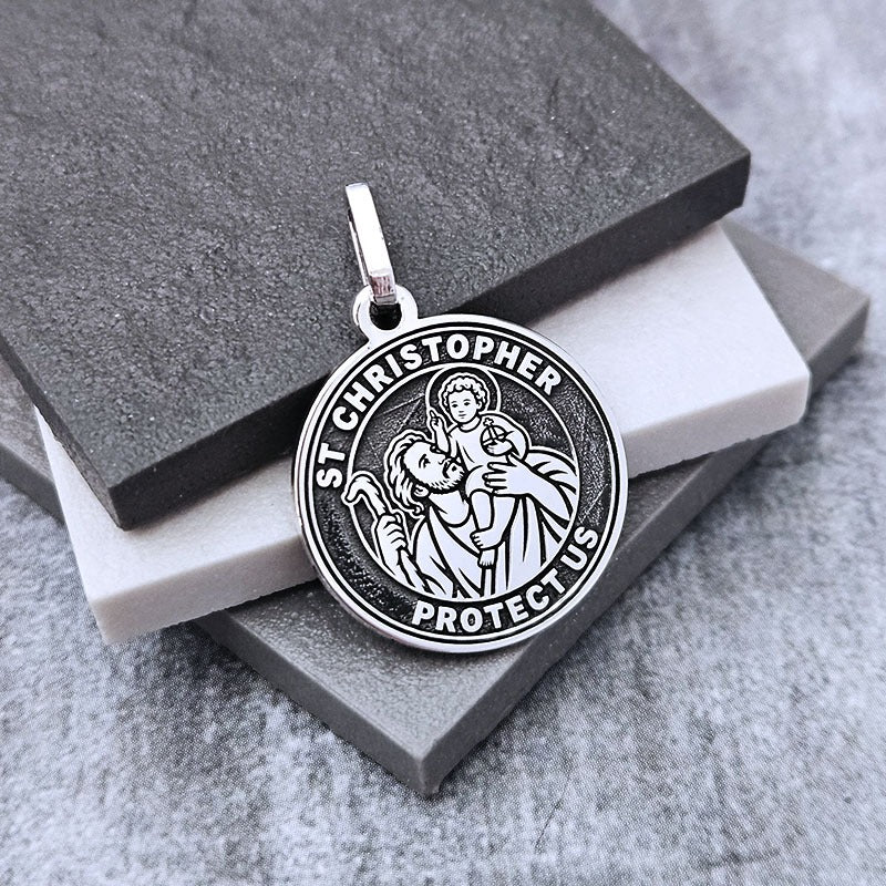 Silver St. Christopher pendant on a gray stone surface