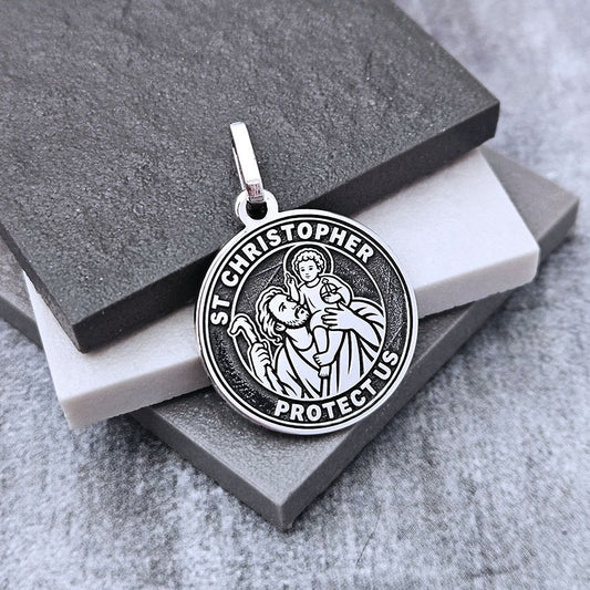 Silver St. Christopher pendant on a gray stone surface