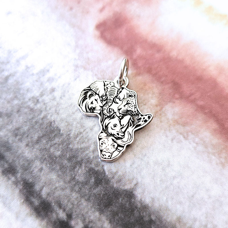 Silver pendant shaped like Africa with animals on a marble background