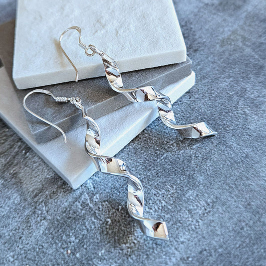 Silver spiral earrings on a textured surface