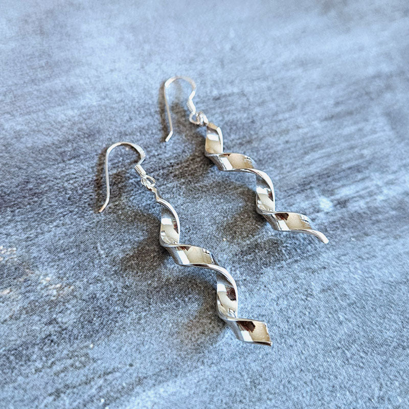 Silver zigzag earrings on a textured gray surface