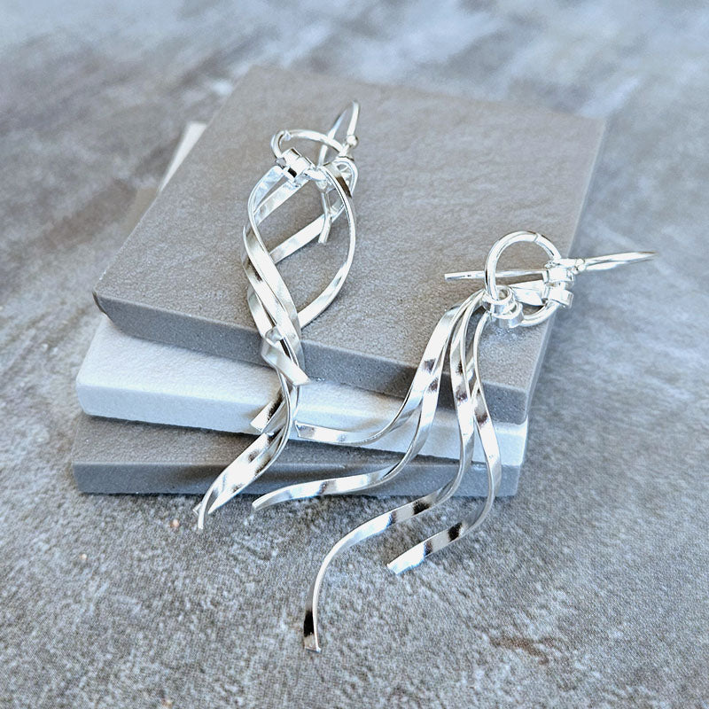 Silver earrings on a gray stone surface