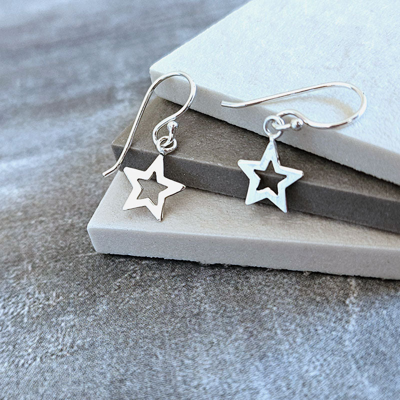 Silver star-shaped earrings on a gray surface