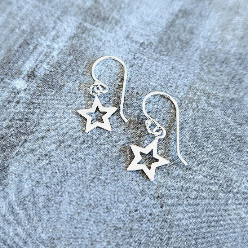 Silver star-shaped earrings on a textured gray surface