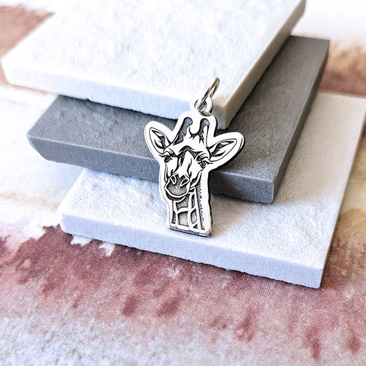 Silver giraffe pendant on a textured surface