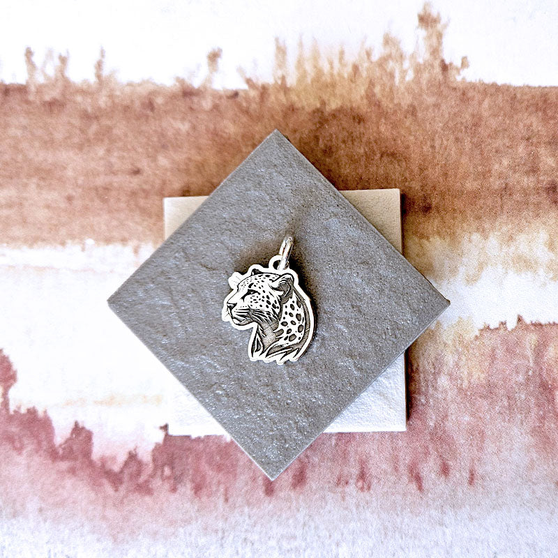 Silver leopard pendant on a textured card with a watercolor background
