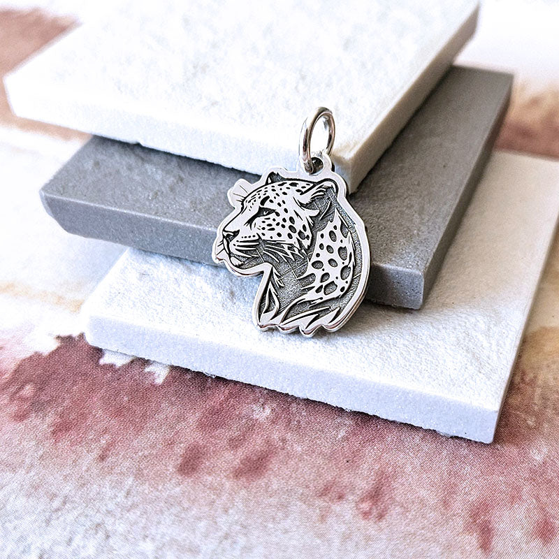 Silver leopard pendant on a textured surface
