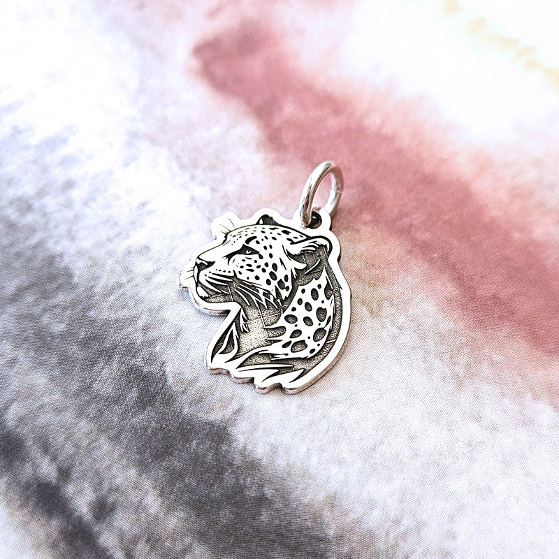 Silver leopard pendant on a textured white and pink background