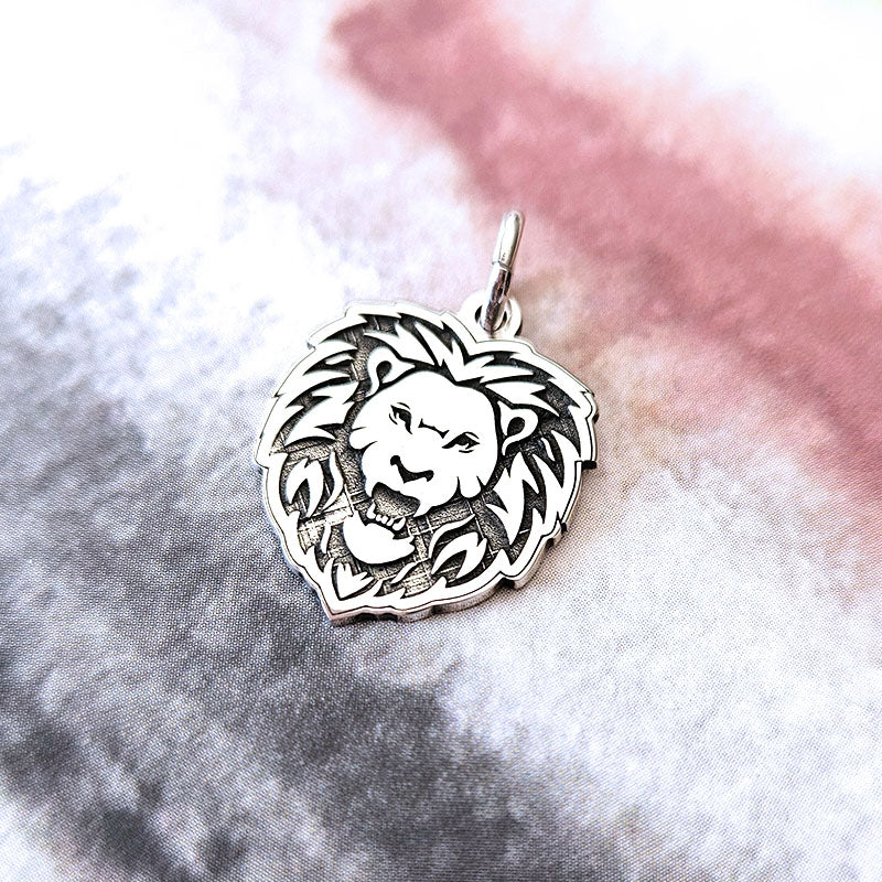 Silver lion head pendant on a textured white and pink background