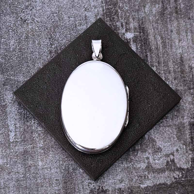 Silver oval locket pendant on a dark stone surface