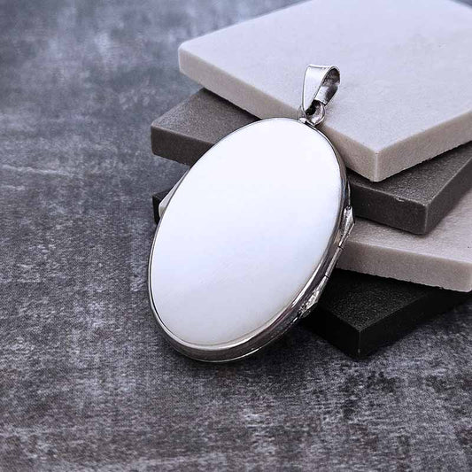 Silver oval locket pendant on a stone surface