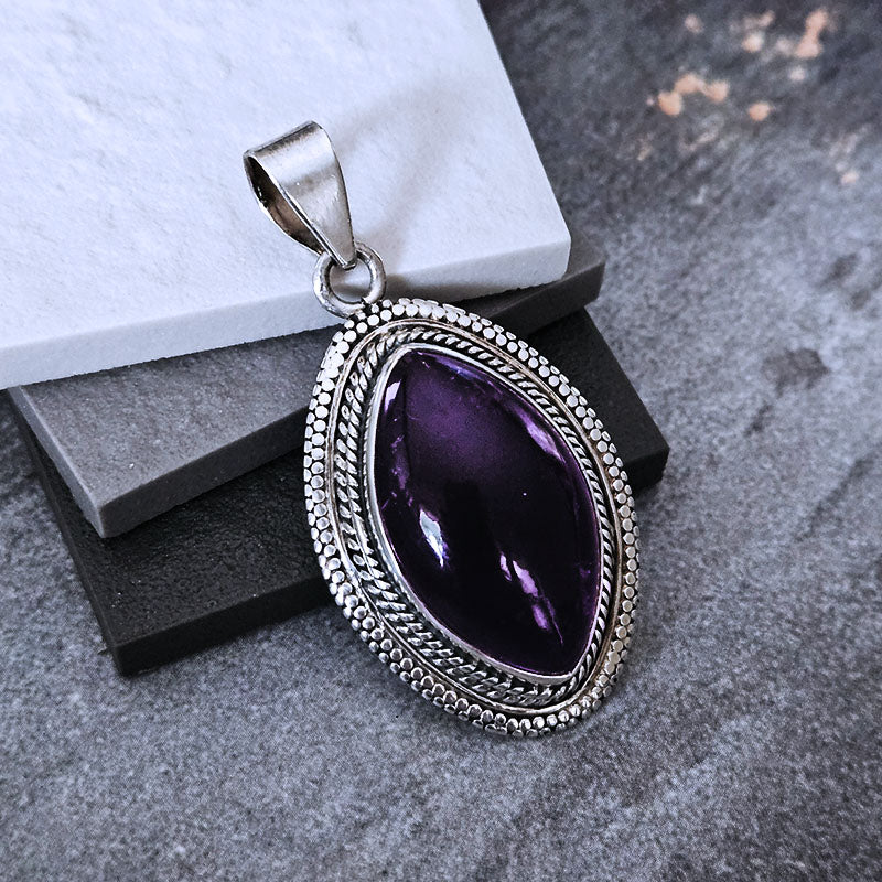 Amethyst pendant with silver setting on a gray surface